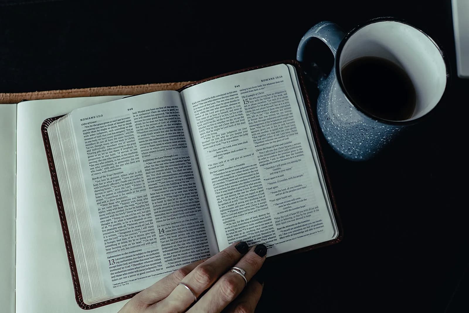 Manos sobre una Biblia abierta junto a una taza